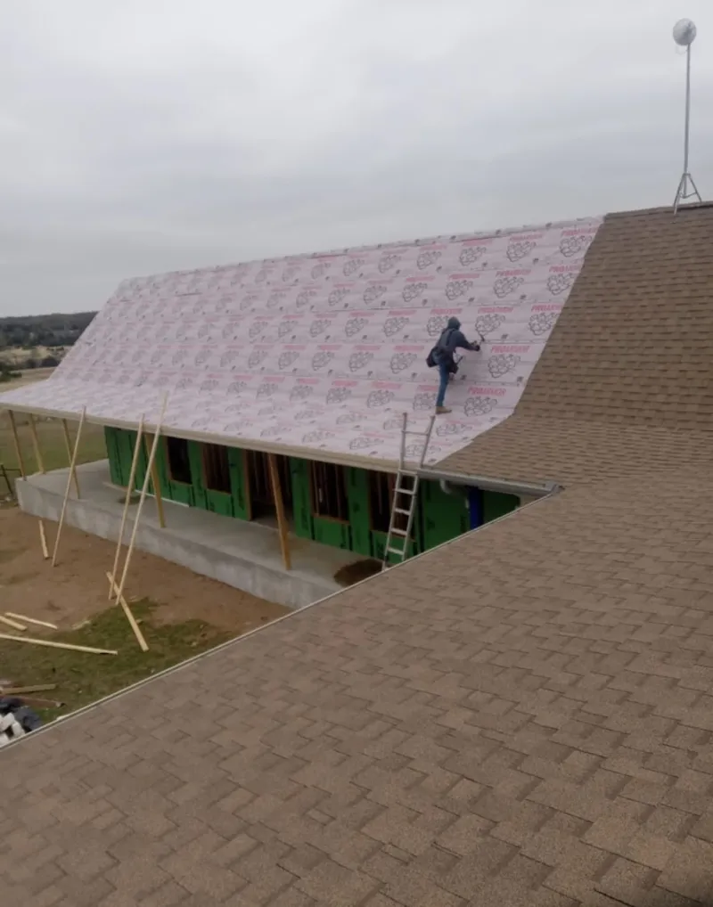 Worker preparing underlayment for a metal roof installation in Beatrice